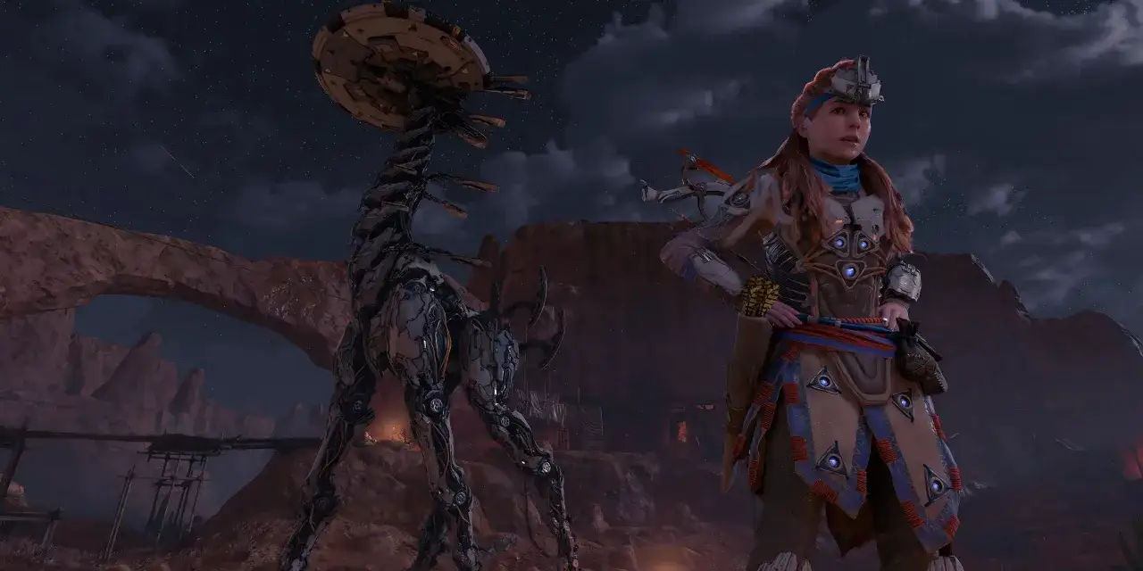 Aloy stoi obok mechanicznego dinozaura pod nocnym, gwiaździstym niebem. To scena z gry Horizon Zero Dawn, gdzie zdobycie platyny jest wyzwaniem.