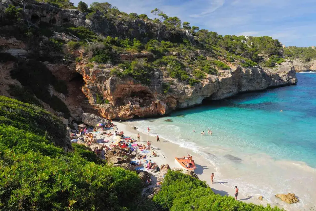 Malownicza zatoka z turkusową wodą i piaszczystą plażą, otoczona klifami. Idealne plaże w Hiszpanii dla spragnionych słońca i relaksu.