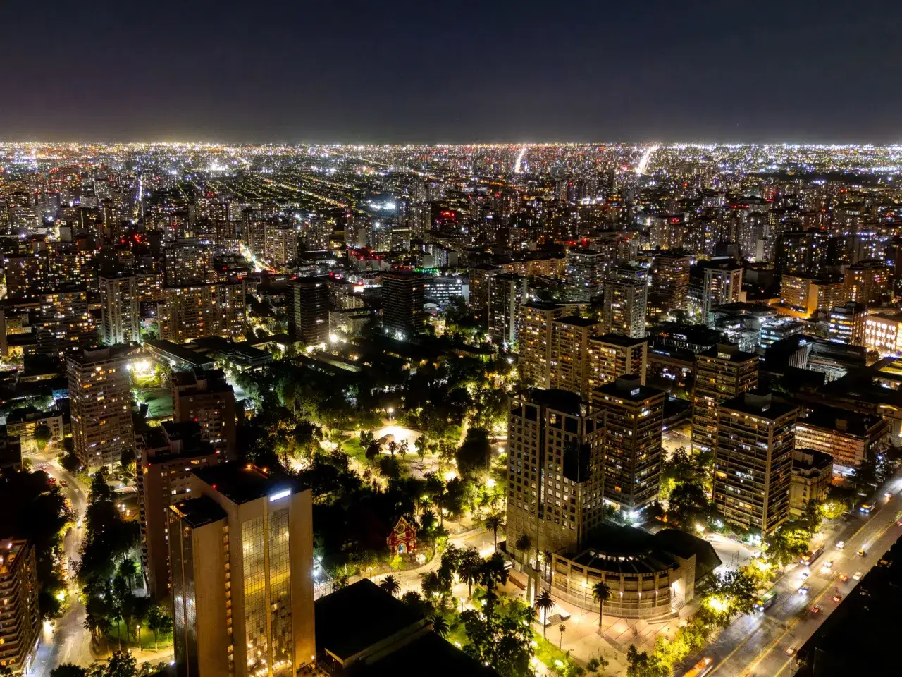 Nocny widok na rozświetlone miasto Santiago de Chile, z mnóstwem budynków i ulic pełnych świateł.