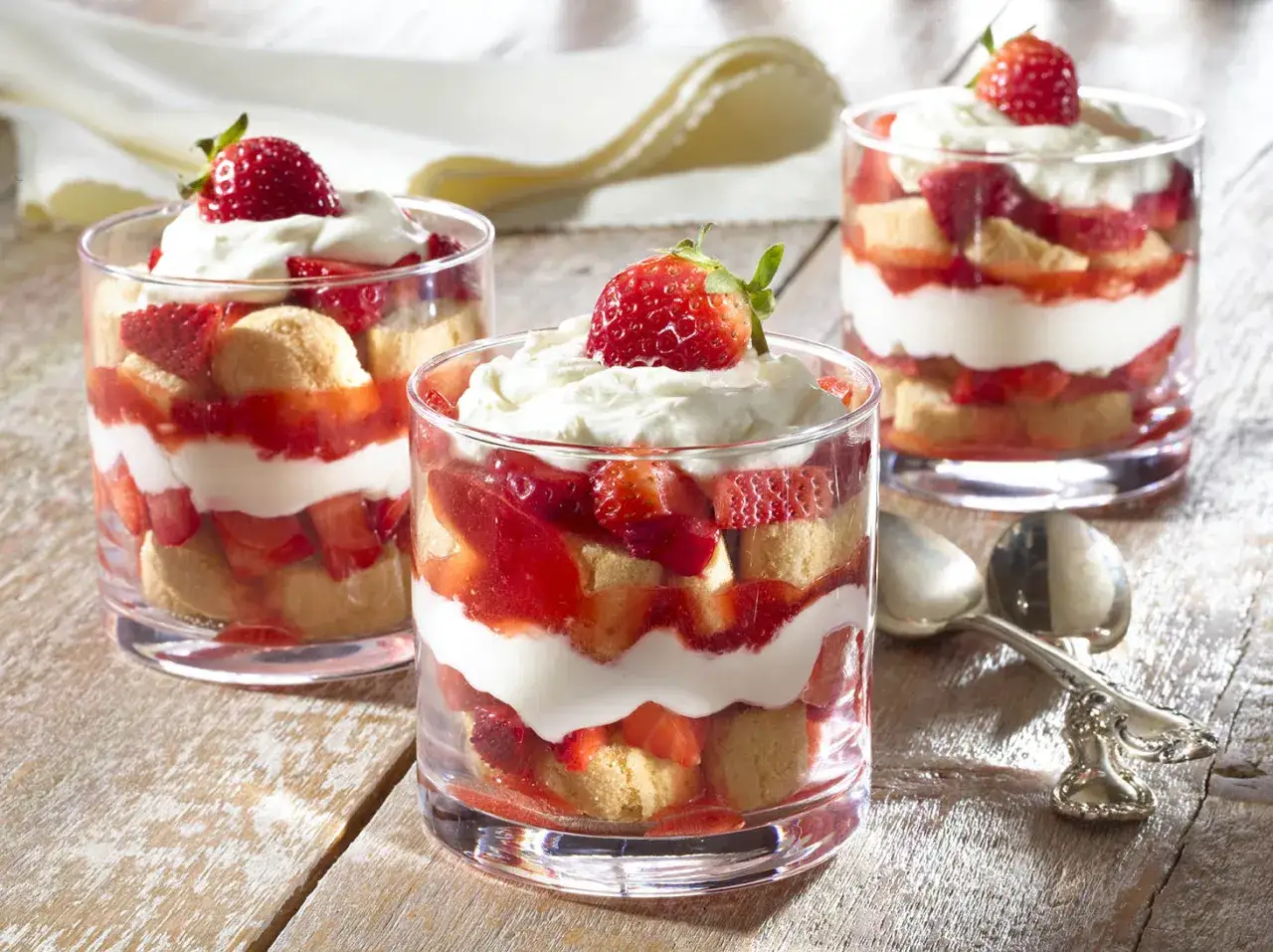 Delicioso tiramisú de fresa en vasos, con capas de bizcocho, crema y fresas frescas, coronado con una fresa entera.
