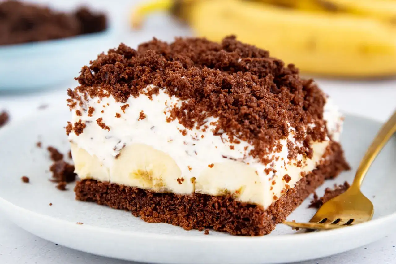 Ein Stück saftiger Maulwurfkuchen vom Blech mit Bananen und Schokostreuseln, bereit zum Genießen.