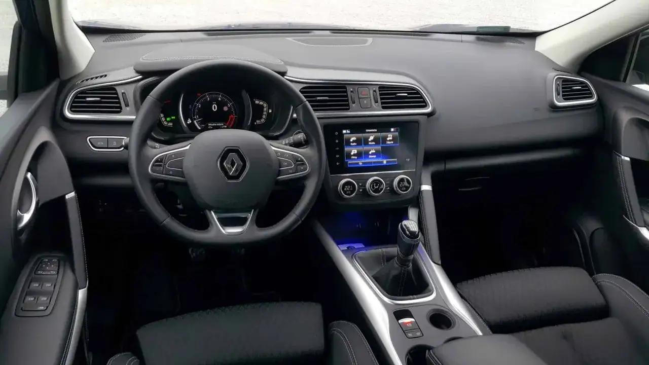 Wnętrze Renault Kadjar, z widocznym ekranem multimediów i cyfrowymi zegarami. Niektórzy kierowcy wskazują na wady ergonomii i materiałów.