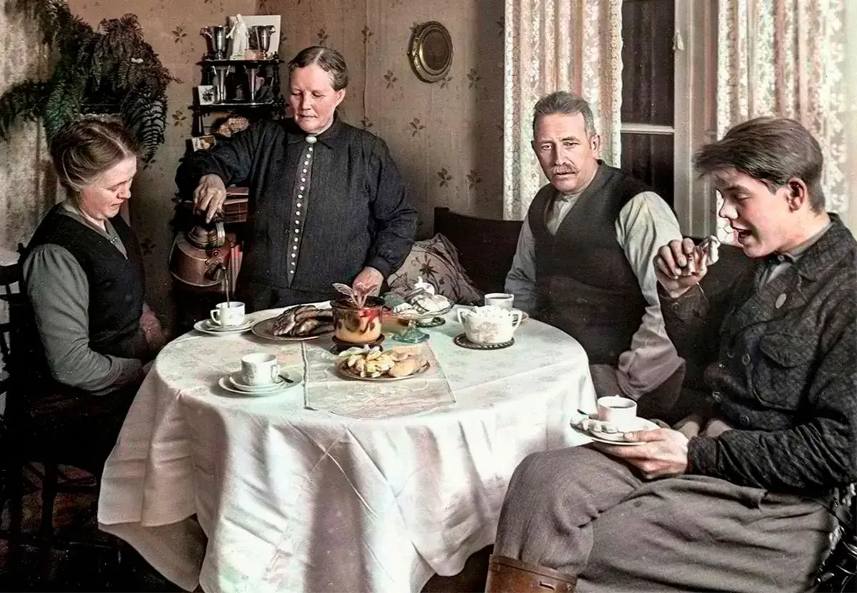 Familj samlad runt bordet f&ouml;r fika. En kvinna h&auml;ller upp kaffe, och det &auml;r sv&aring;rt att s&auml;ga vilka som dricker mest kaffe, men alla ser ut att njuta.