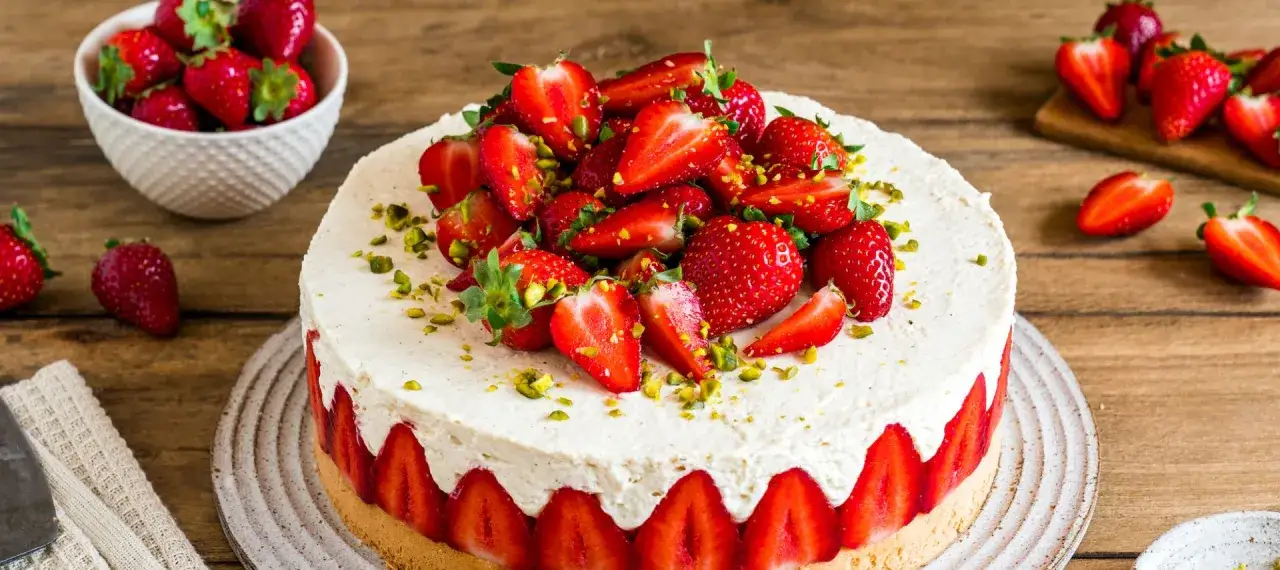 Eine köstliche Erdbeertorte, üppig belegt mit frischen Erdbeeren und gehackten Pistazien, verlockt zum Genuss.
