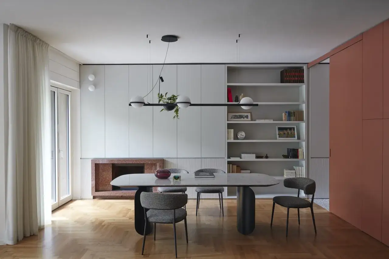 Sala da pranzo moderna con tavolo ovale, sedie imbottite e libreria a giorno. Le pareti grigio luminoso creano un'atmosfera sofisticata.