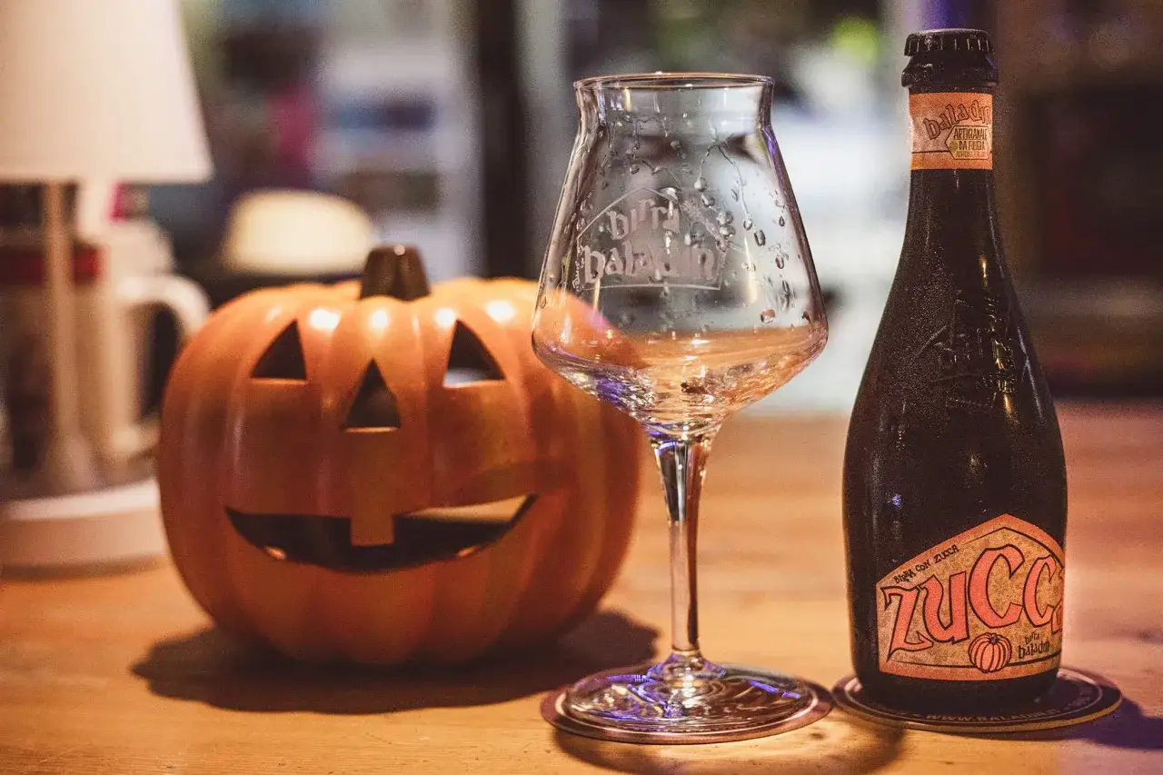 Zucca sorridente e una bottiglia di birra alla zucca, pronte per Halloween.