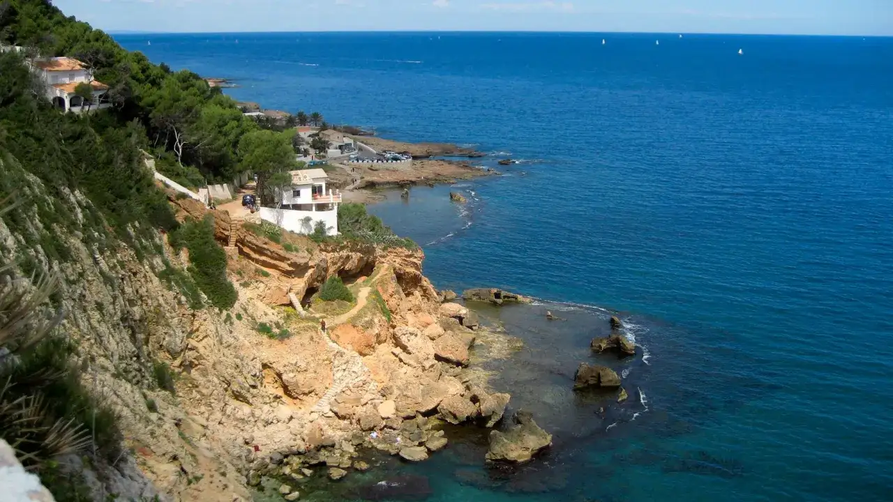 Felsige K&uuml;ste mit wei&szlig;en H&auml;usern und Pinienw&auml;ldern, das blaue Meer glitzert. Ein malerischer Blick auf Denia Costa Blanca.