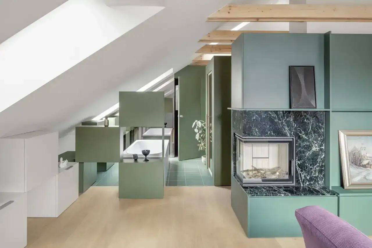Pareti divisorie mansarda in verde salvia creano un ambiente moderno con vasca da bagno a vista e camino.