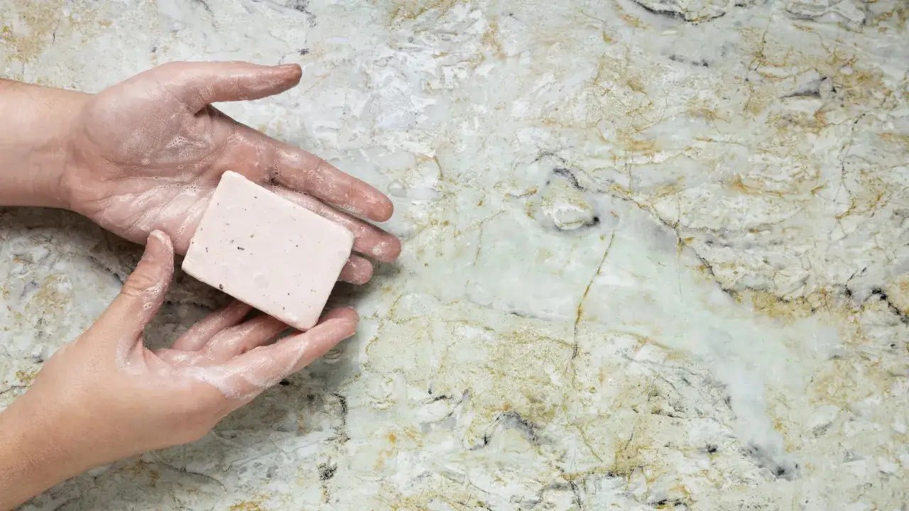 Mani insaponate con una saponetta, pronte per creare un detersivo per marmo fatto in casa.