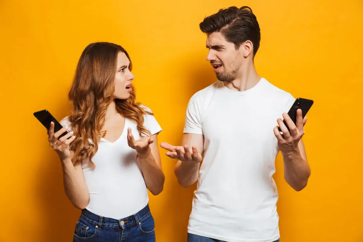 Coppia con smartphone, espressioni confuse, forse un litigio. Come farsi cercare dopo un litigio?