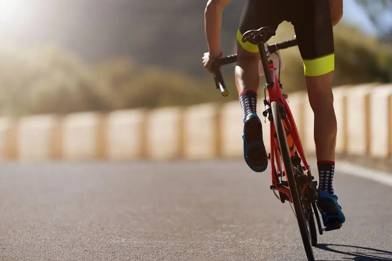 Cyclist powering up a hill, legs pumping hard. This image captures the intensity of a sprint workout plan.