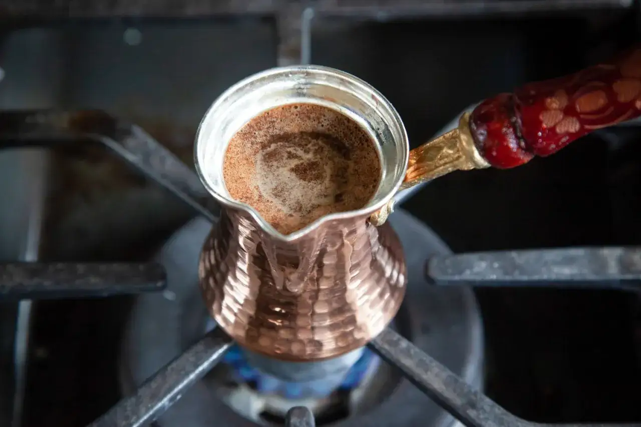Kupferne Mokkakanne mit aufsch&auml;umendem Mokka-Kaffee auf dem Herd.
