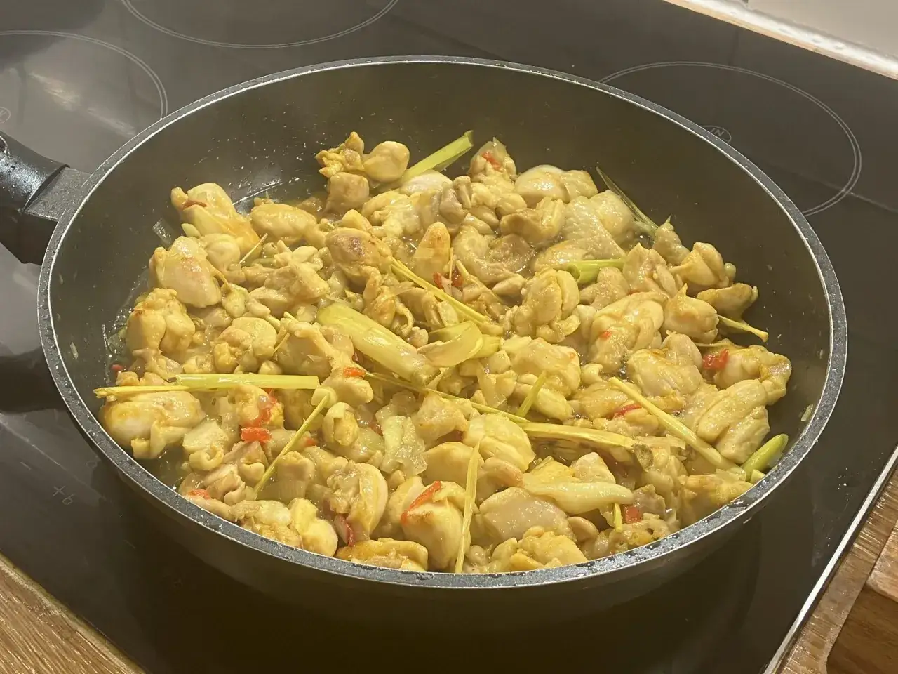 Stekt vietnamesisk kyckling med citrongr&auml;s och chili i en stekpanna.