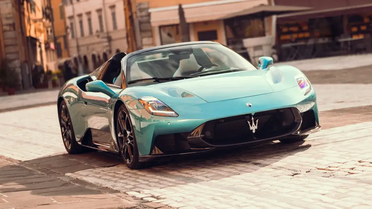 Błękitny Maserati MC20 Cielo na brukowanej uliczce, z widocznym logo marki.