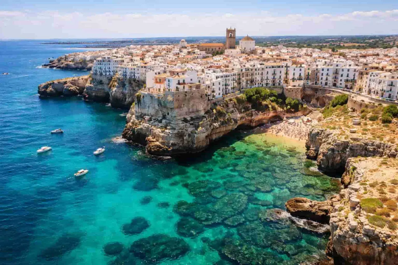 Vue aérienne de Polignano a Mare, une ville perchée sur des falaises calcaires. Ses maisons blanches surplombent la mer Adriatique aux eaux turquoise. Une petite plage bondée se niche dans une crique. Un paysage des Pouilles à éviter pour ceux qui cher...