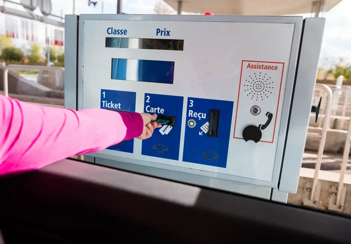 Une main ins&egrave;re une carte dans une borne de **classe autoroute** pour payer.