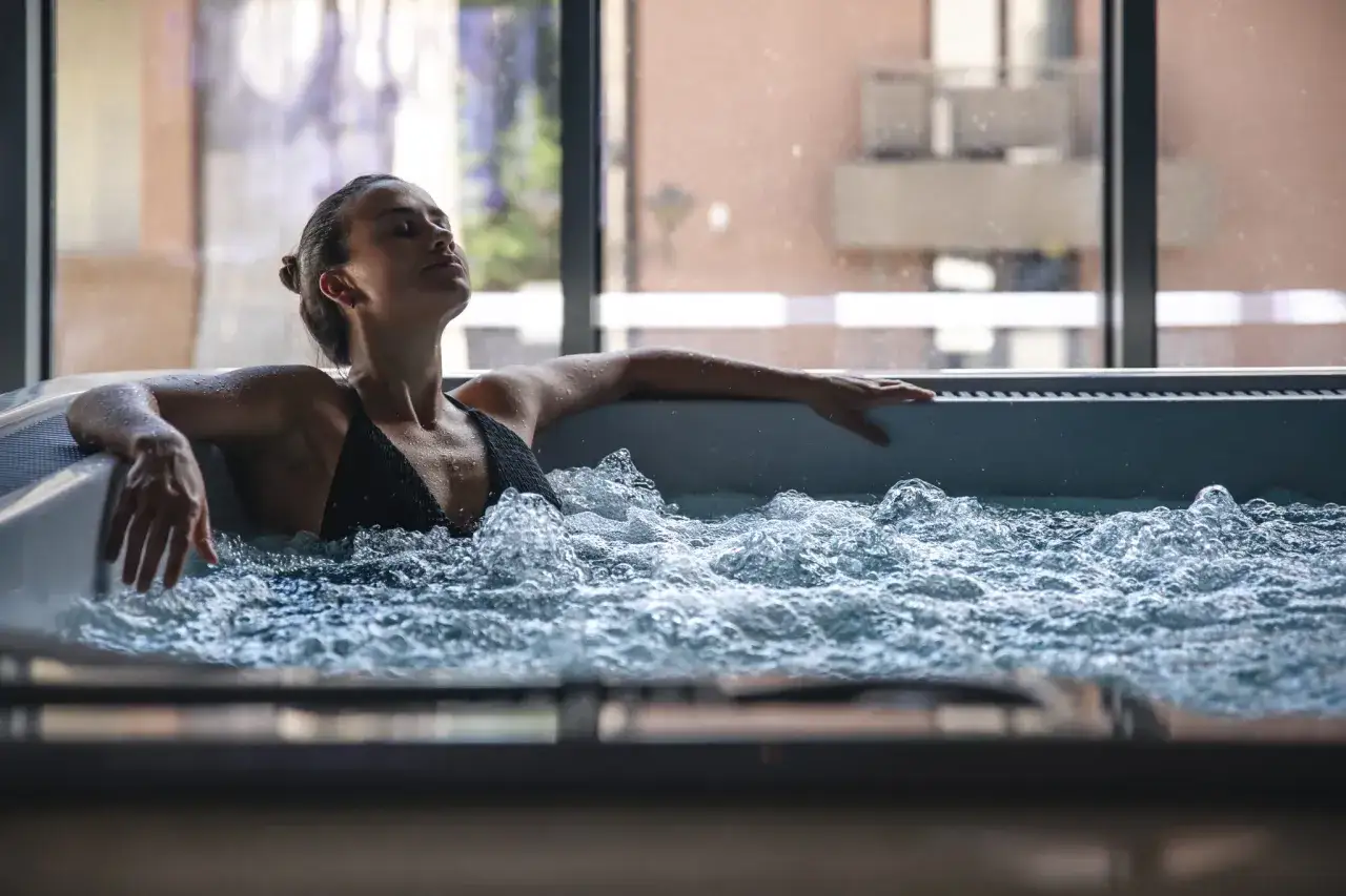 Femme détendue dans un jacuzzi, profitant des bulles. Attention aux contre-indications jacuzzi pour certaines conditions médicales.
