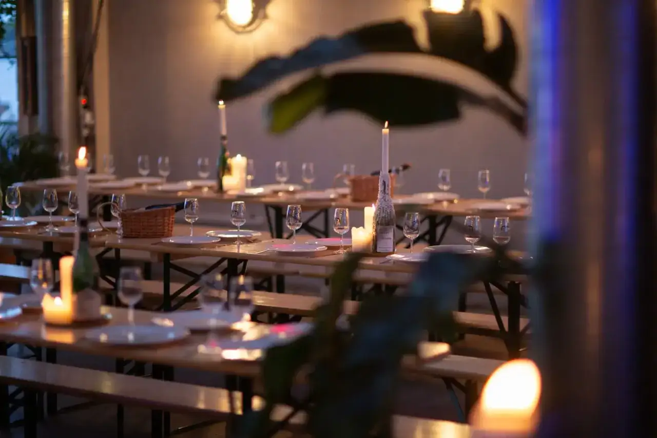 Tavoli apparecchiati con bicchieri e candele accese, pronti per una cena speciale al Mikkeller di Copenhagen.