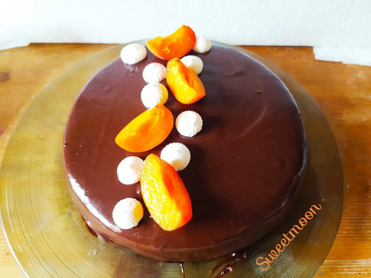 Torta Sacher lucida e invitante, decorata con spicchi d'arancia e meringhe bianche.