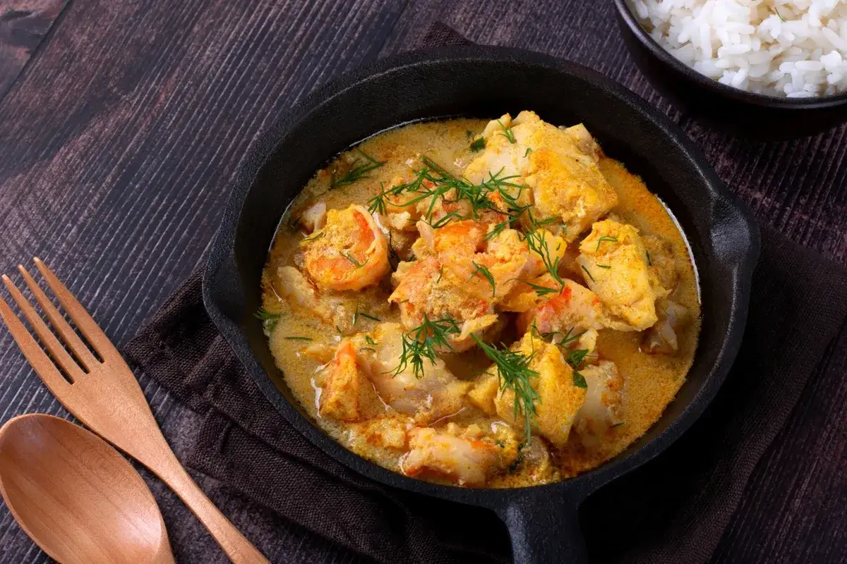 Kremowe curry z krewetkami i rybą, idealne jako inspiracja, co ugotować w piątek. Podane z ryżem.