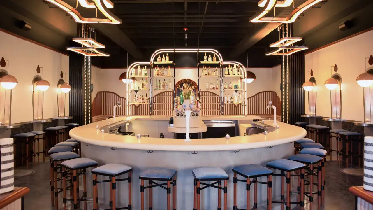Nowoczesny drink bar z półkami pełnymi alkoholi i wygodnymi stołkami. Idealne miejsce, by dowiedzieć się, jak założyć drink bar.