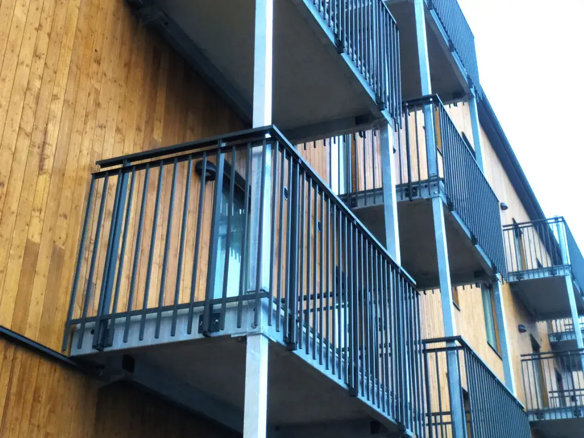 Nowoczesne balkony dostawne z metalową balustradą na drewnianej elewacji. Sprawdź atrakcyjną cenę!