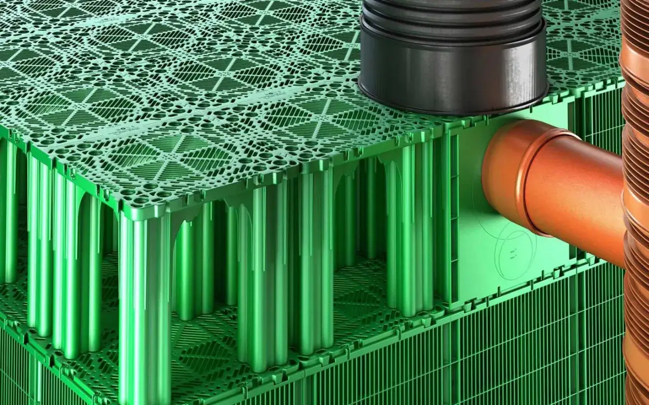 Zielone moduły systemu do odprowadzenia wody z rynien, z pomarańczową rurą wchodzącą do środka.