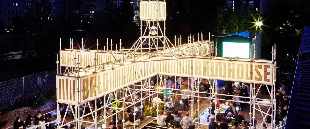 Nachts belebt sich das **brlo gleisdreieck** mit Menschen, die unter einer beleuchteten Konstruktion feiern.