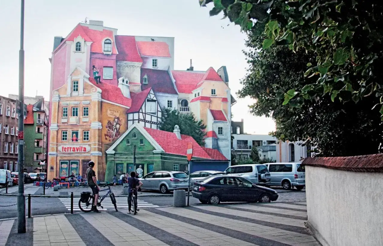 Kolorowy mural na budynku, przypominający o historii i tradycji, jakby odzwierciedlał proces gentryfikacji.