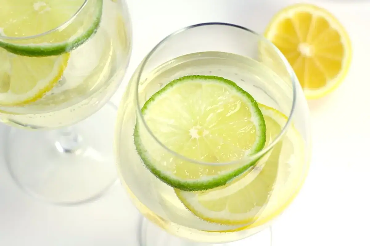 Orzeźwiające wino ze spritem z plasterkami limonki i cytryny w kieliszkach. Idealne na letnie popołudnie.
