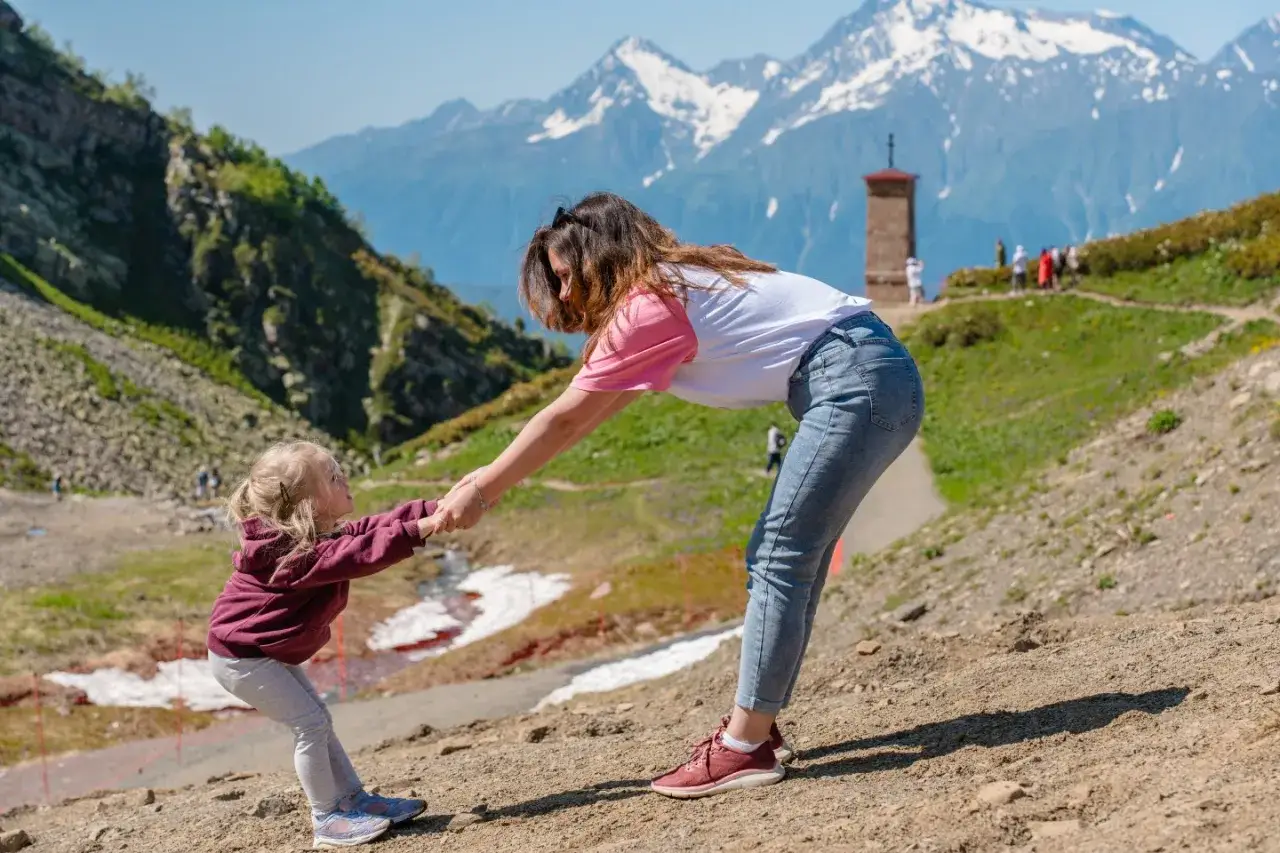 Mama i 3-letnia córka trzymają się za ręce na tle gór. Radosne chwile w Zakopanem.