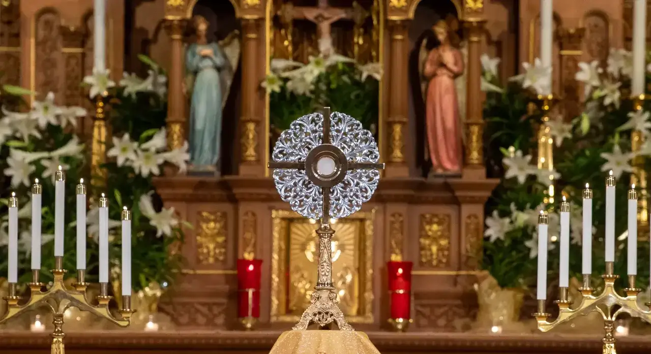 A monstrance with the Host is displayed on an altar, surrounded by lilies and lit candles. This sacred scene inspires contemplation on how to evangelize with faith and devotion.