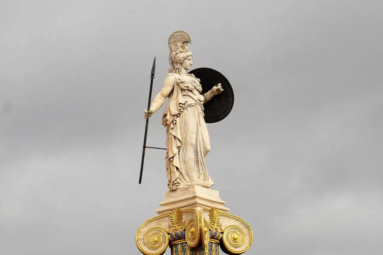 Statue d'une déesse de la guerre, casquée, tenant une lance et un bouclier, sur un chapiteau orné.