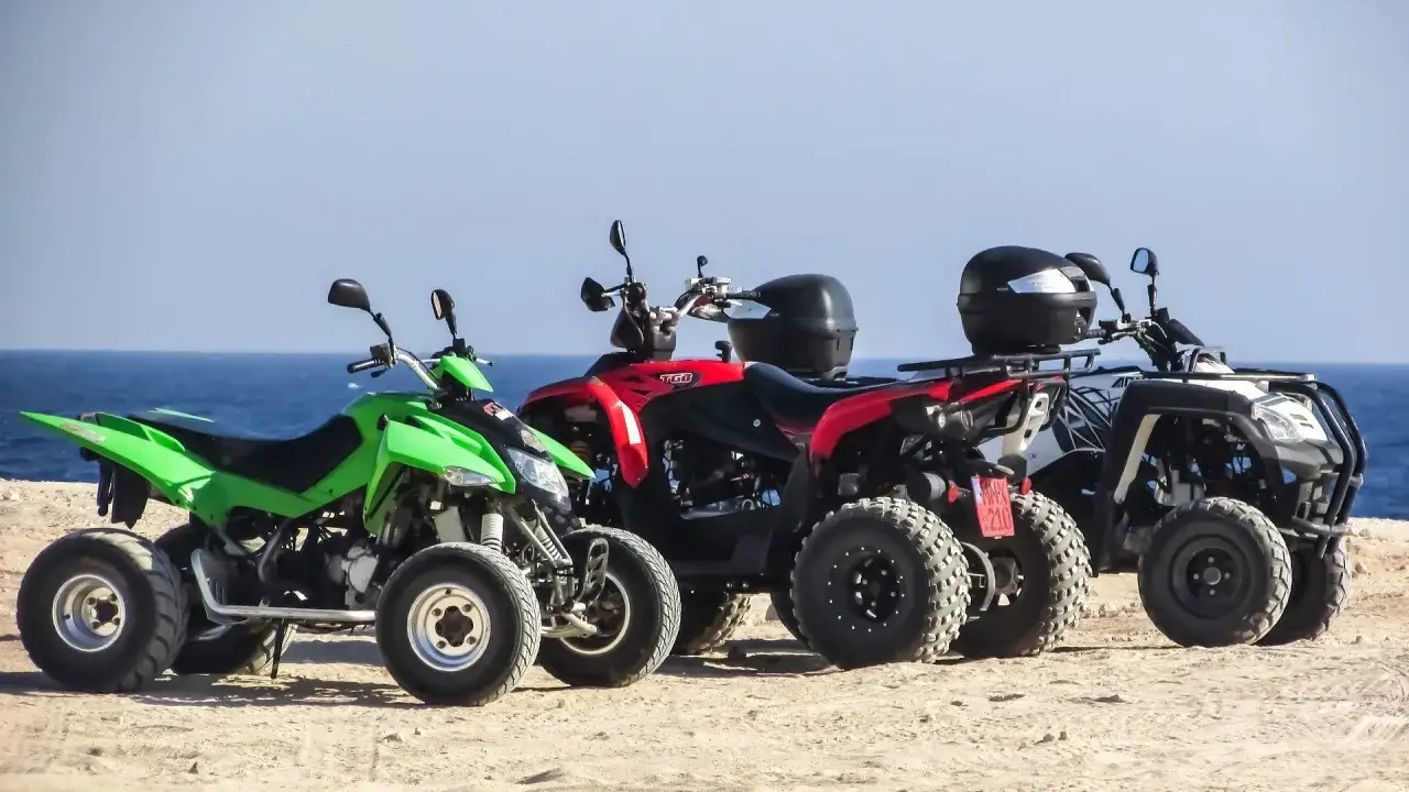 Zielony, czerwony i biały quad na plaży. Zastanawiasz się, jakie prawo jazdy na quada 125?