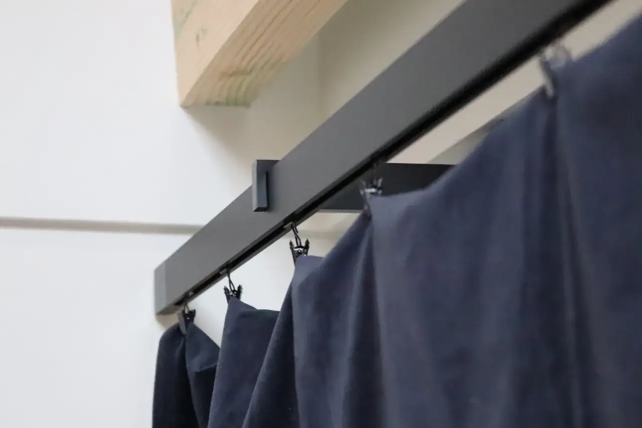 Nowoczesny, czarny karnisz apartamentowy z zasłonami, idealny do minimalistycznych wnętrz.