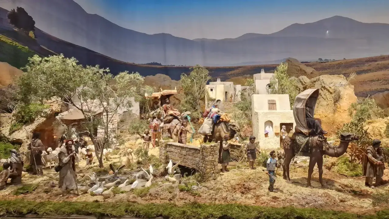 Belén del Ayuntamiento de Valencia con figuras de camellos, ovejas y personas en un paisaje desértico.