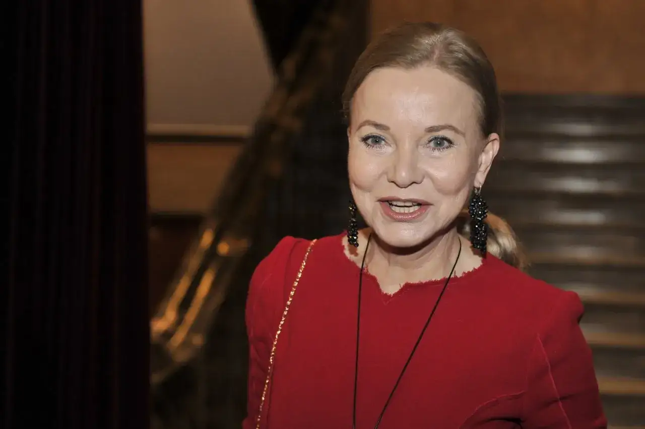 Uśmiechnięta kobieta w czerwonej sukience, z długimi blond włosami i czarnymi kolczykami. Ciekawe, ile lat ma Laura Łącz.