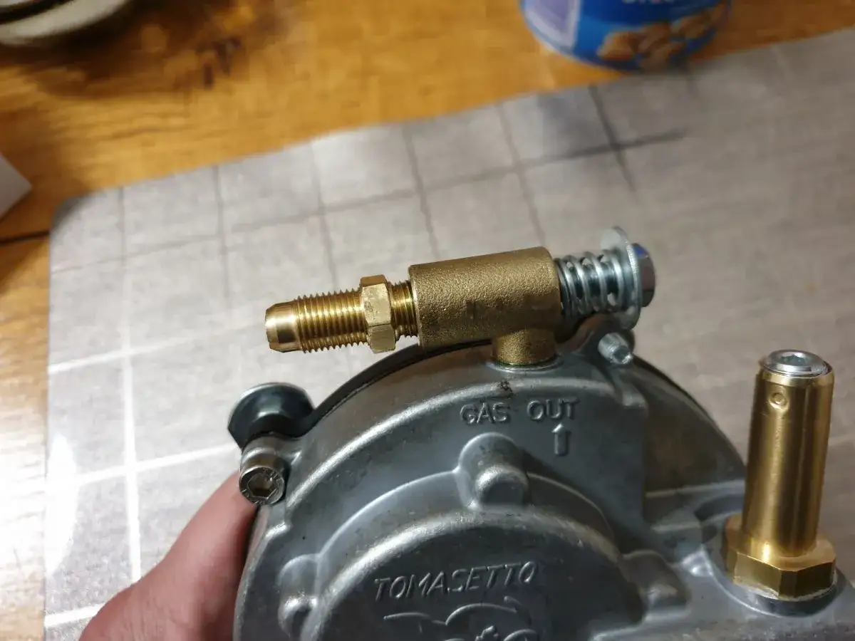 Elementy do przeróbki agregatu na gaz: mosiężny króciec, sprężyna i zawór.