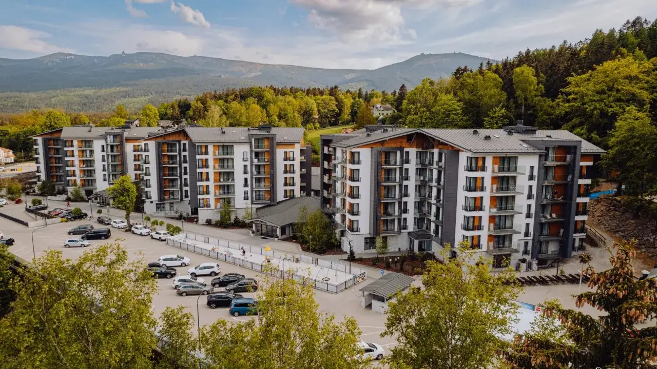 Nowoczesny hotel Blue Mountain w Szklarskiej Porębie, otoczony zielenią, z widokiem na góry.