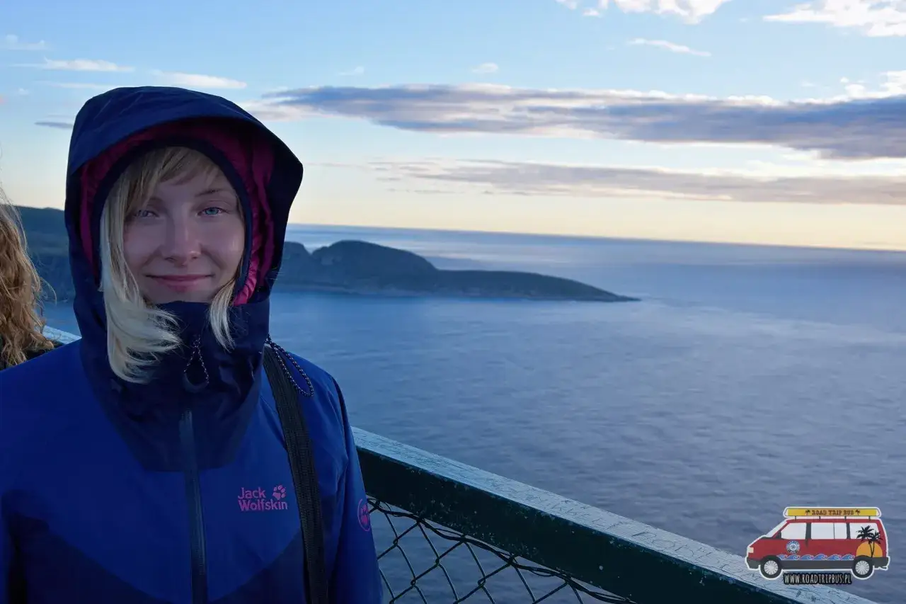 Dziewczyna w kurtce Jack Wolfskin, która chroni przed wiatrem i deszczem, bo texapore to właśnie materiał wodoodporny i oddychający. W tle ocean i wyspa.