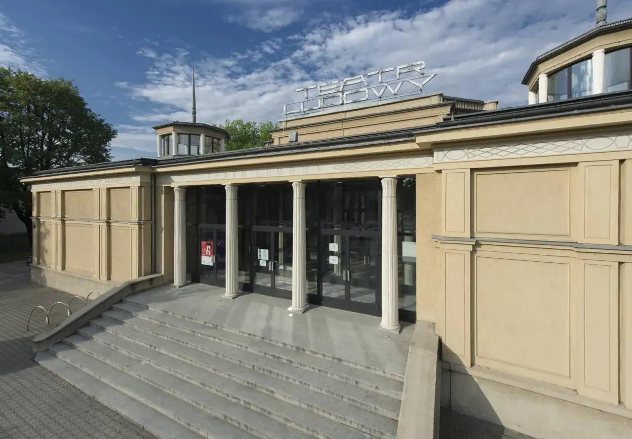 Teatr Ludowy zaprasza na swoje spektakle. Elegancka fasada z kolumnami i schodami prowadzącymi do wejścia.