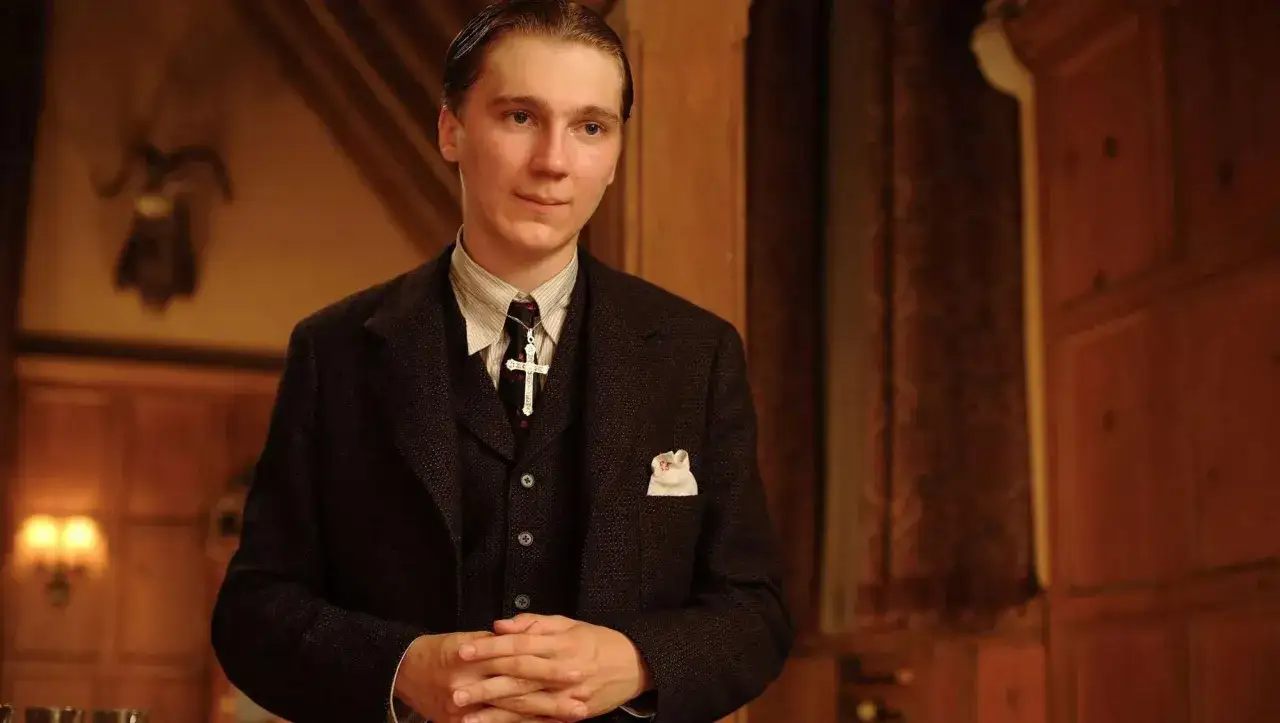 Paul Dano i mörk kostym med en korshalsband och näsduk i bröstfickan.