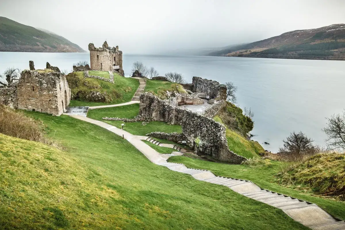 Ruinas de un castillo en un acantilado junto a un lago, ideal para un viaje a Escocia de 7 días.