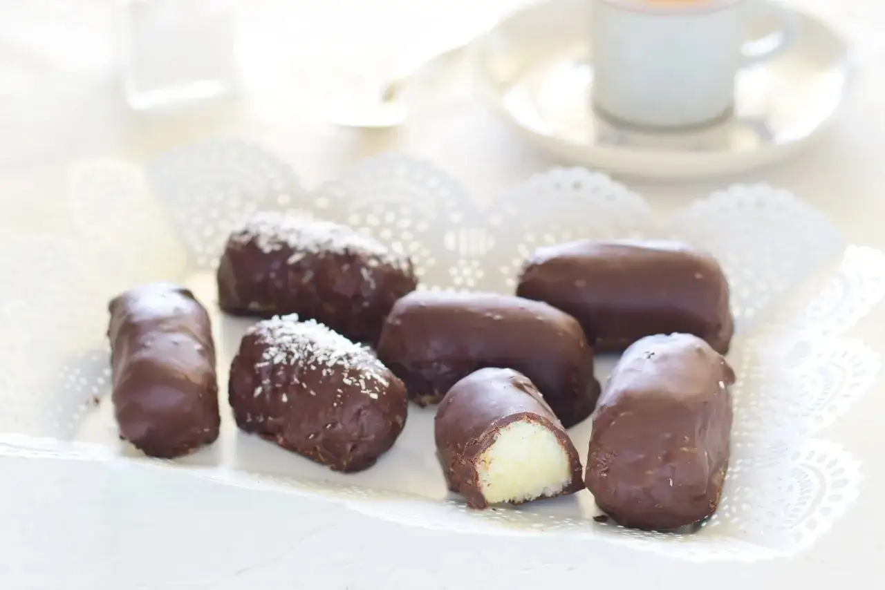 Deliziosi dolcetti ricoperti di cioccolato, alcuni con scaglie di cocco. Un morso rivela un cuore morbido e profumato di palline di cocco.
