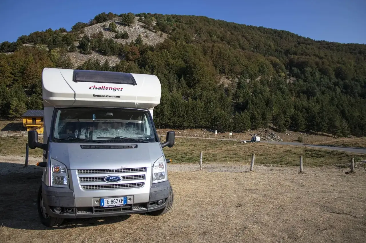 Un camper Challenger parcheggiato in un'area panoramica con una collina boscosa sullo sfondo. Un'avventura in Calabria in camper.