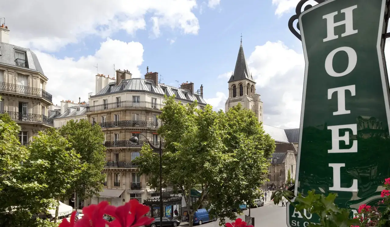 Vue d'un quartier parisien avec des immeubles haussmanniens, une église et un panneau