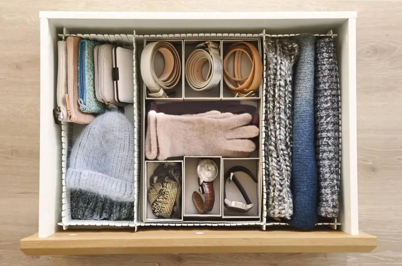 Cajón organizado con el método Marie Kondo: gorro, guantes, cinturones, carteras y bufandas dobladas.
