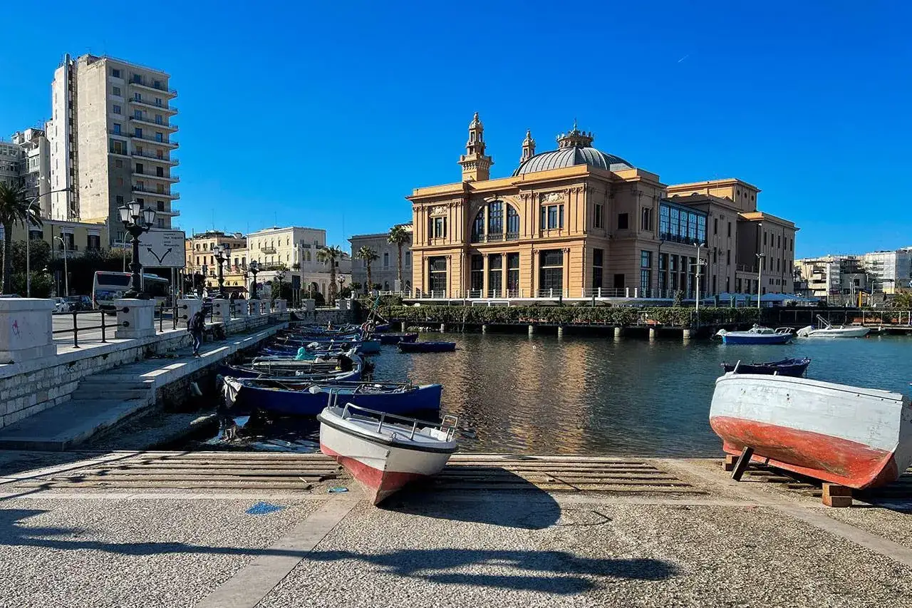 Il Teatro Petruzzelli e il lungomare di Bari, con barche ormeggiate e un edificio moderno sullo sfondo. Un'ottima immagine per scoprire le cose da vedere a Bari.