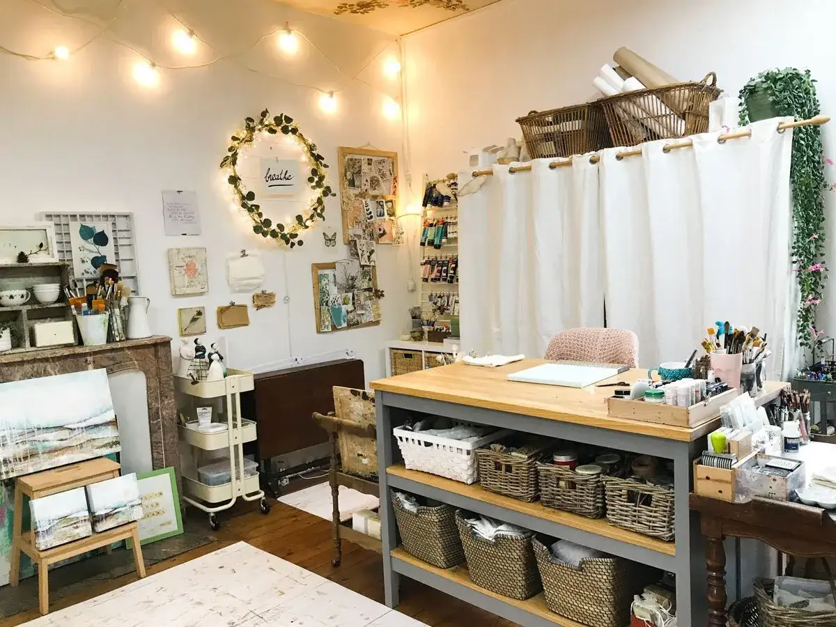 Acogedor estudio de pintura en casa, lleno de materiales art&iacute;sticos, lienzos y una inspiradora guirnalda de luces.