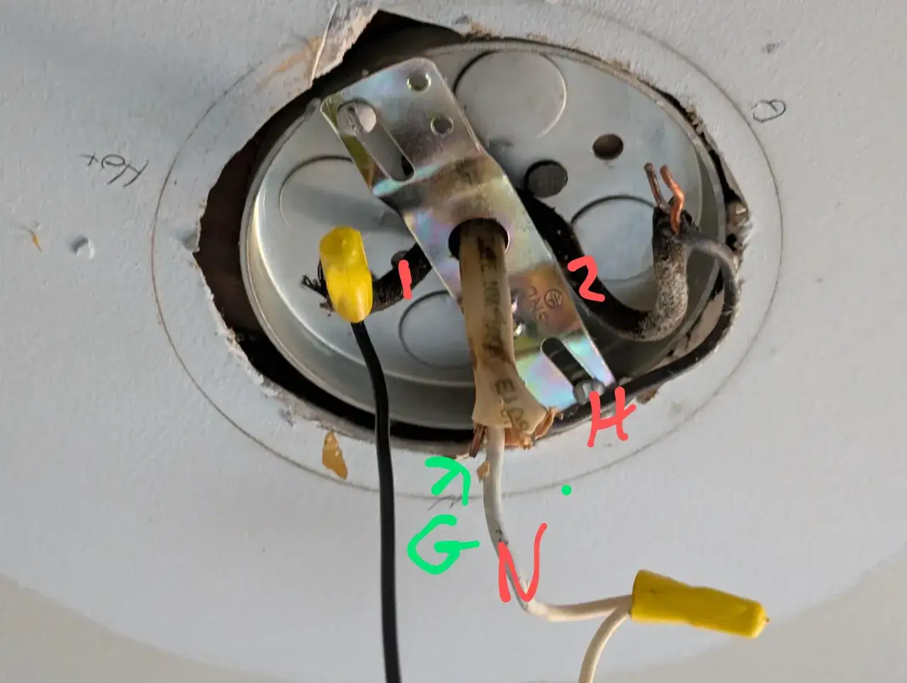 Instrucciones para como cambiar una lampara de techo: cables de alimentación (1, 2), tierra (G), neutro (N) y caliente (H) expuestos en caja de techo.